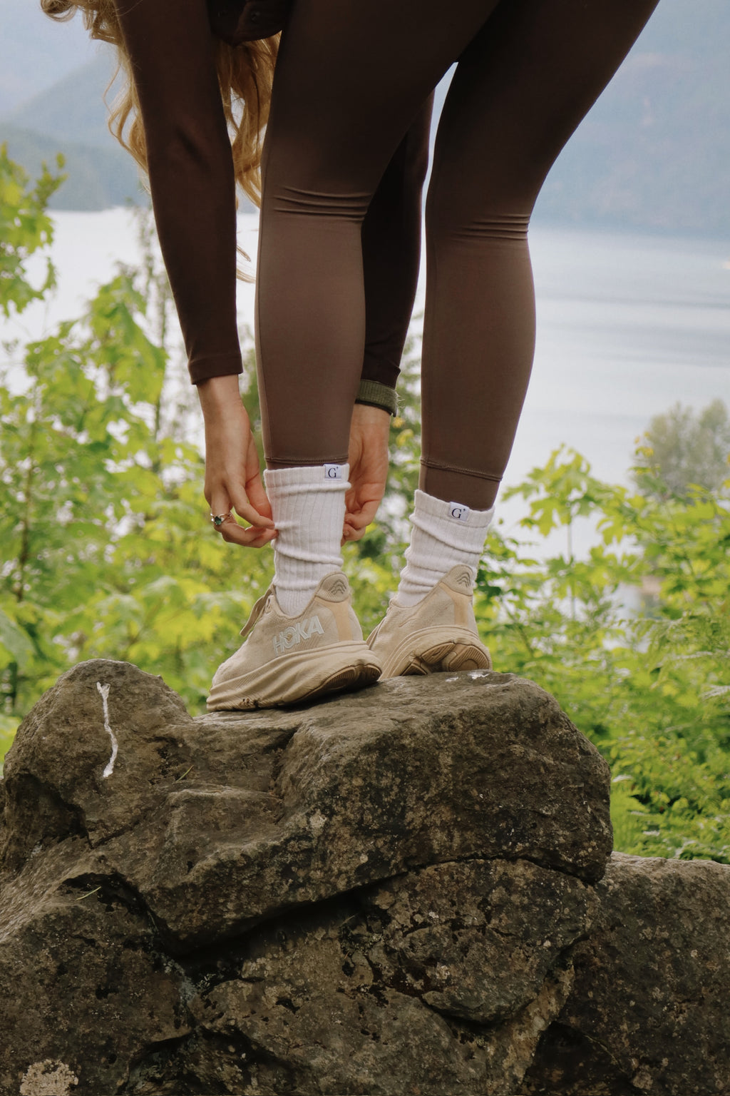 Person wearing brown leggings and beige shoes on a rock with a natural background